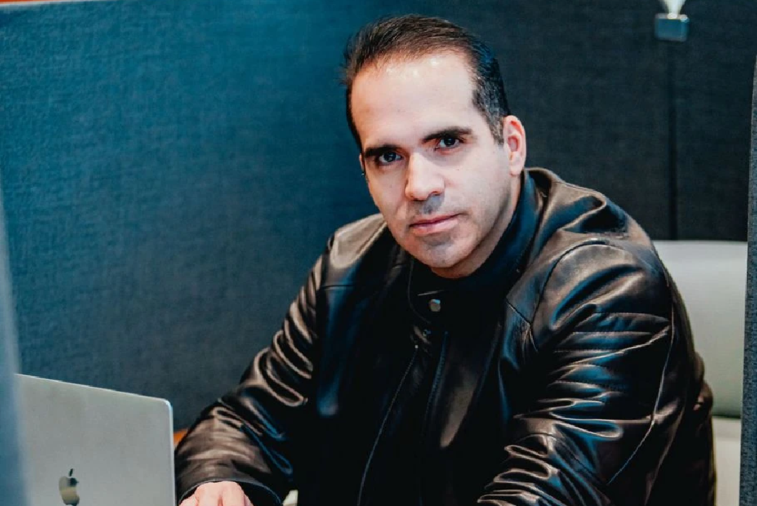Manuel Alejandro Rojas Aparicio in a black leather jacket working at an Apple laptop